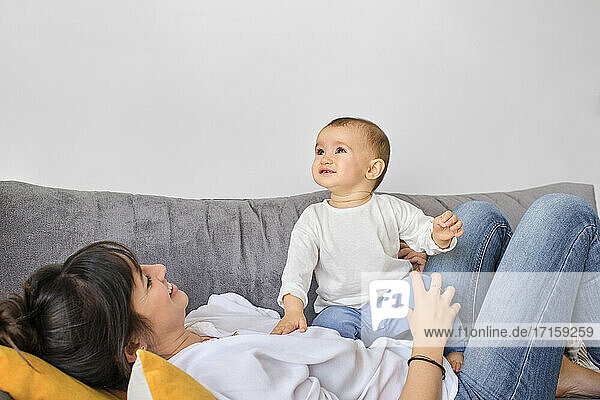 Mother playing with baby daughter on sofa
