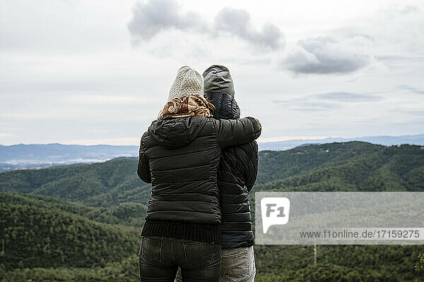 Paar umarmt  während Blick auf Berge gegen den Himmel im Winter