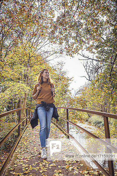 Mature woman walking on bridge in forest