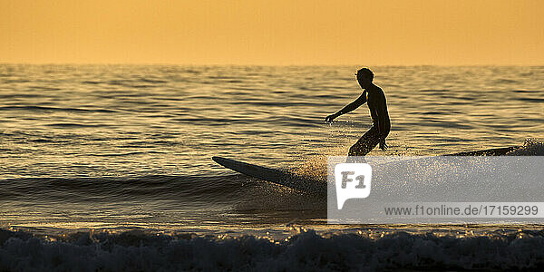 Silhouette Mann beim Surfen auf dem Meer gegen den klaren Himmel bei Sonnenuntergang  Pembrokeshire  Wales  UK