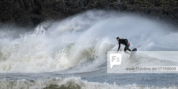 Älterer Mann surft auf den Wellen und plantscht im Meer  Broad Haven South Beach  Wales  UK