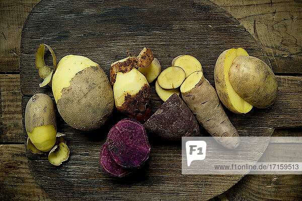 Different types of potatoes: Glorietta  purple sweet potato  Agria  Annabelle  Bamberger Hoerndl  Gala on rustic wooden background