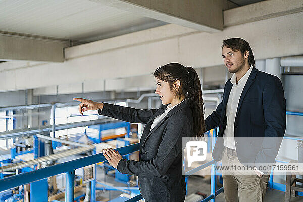 Businesswoman pointing while standing by colleague at industry