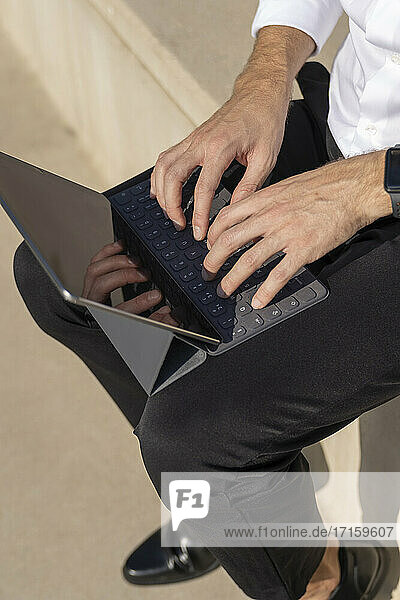 Male entrepreneur using digital tablet while sitting on steps