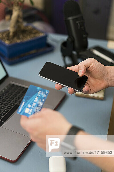 Geschäftsmann mit Kreditkarte beim Einkaufen über das Mobiltelefon zu Hause