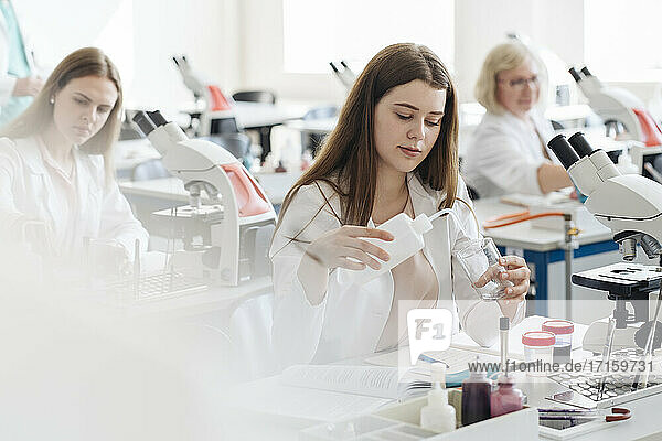 Researchers in white coats working in science class