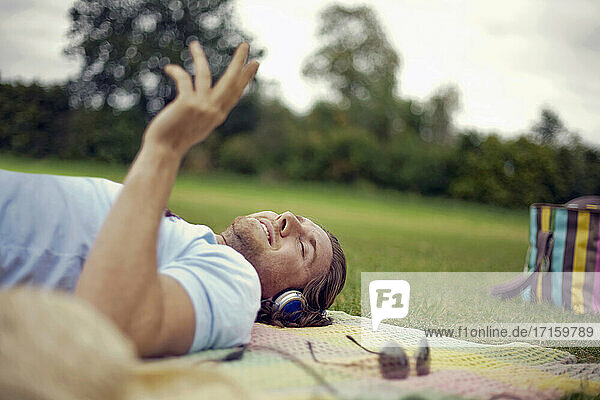 Young man listening music while lying down at park