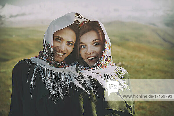Excited lesbian couple with headscarf at meadow