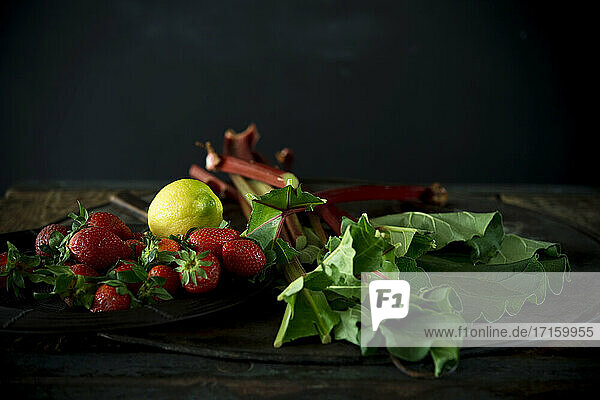 Studioaufnahme von frischen Rhabarberstängeln  Erdbeeren und einer Zitrone