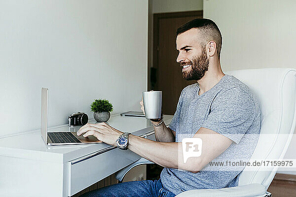 Lächelnder Mann arbeitet zu Hause am Laptop