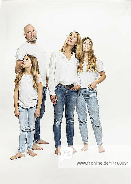 Daughters with parents looking away while standing in studio