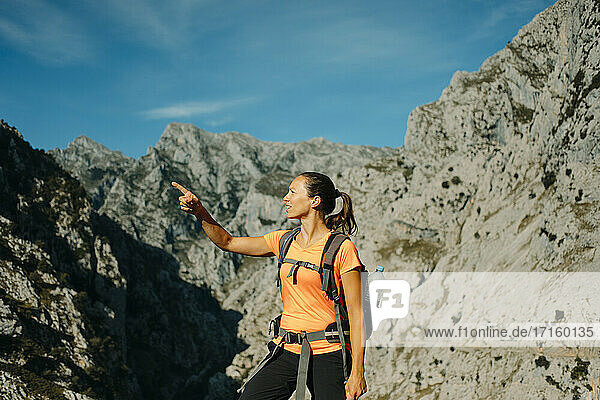 Mid adult woman gesturing while standing against mountain range at Cares Trail in Picos De Europe National Park  Asturias  Spain