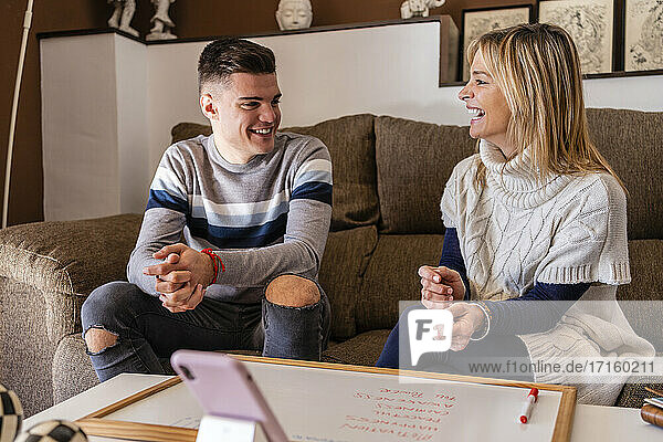 Weiblicher Berater und junger Mann lachen während einer Motivationssitzung am Arbeitsplatz