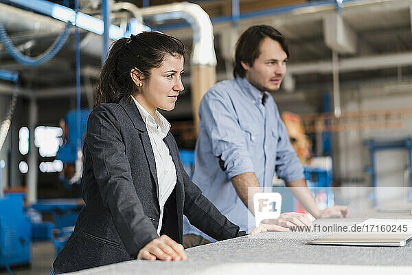 Young businesswoman looking away while standing with colleague at industry