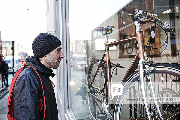 Mature man looking at new bicycle through store window
