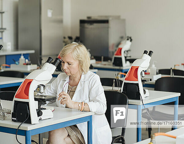 Senior female researcher in a white coat working in lab
