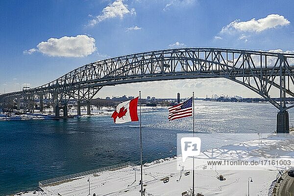 Port Huron  Michigan - Die Flaggen der USA und Kanadas wehen an der Blue Water Bridge  die die Vereinigten Staaten (rechts) und Kanada über den St. Clair River am südlichen Ende des Huron-Sees verbindet.