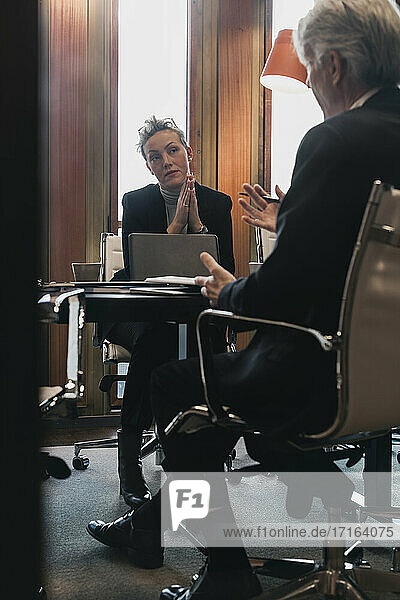 Senior businessman planning strategy with businesswoman at conference table in board room
