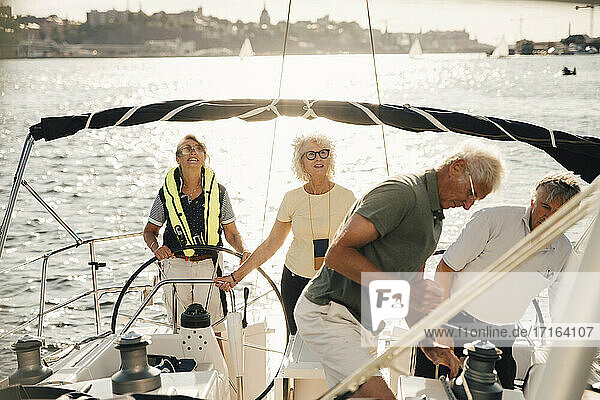 Senior männliche und weibliche Freunde Segelboot auf sonnigen Tag im Meer