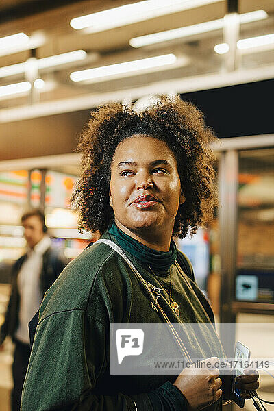 Lächelnde Studentin blickt auf beleuchtete U-Bahn