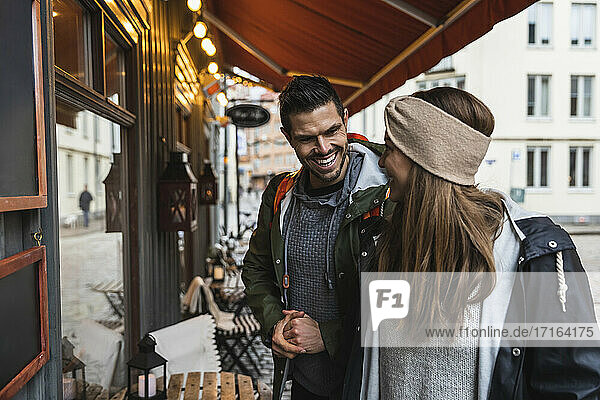 Lächelndes Paar beim Schaufensterbummel  während es vor einem Geschäft steht