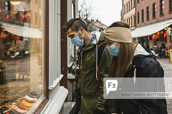 Heterosexuelles Paar beim Schaufensterbummel vor einem Geschäft während einer Pandemie