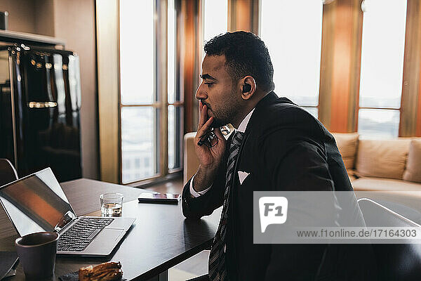 Worried businessman looking at laptop in board room