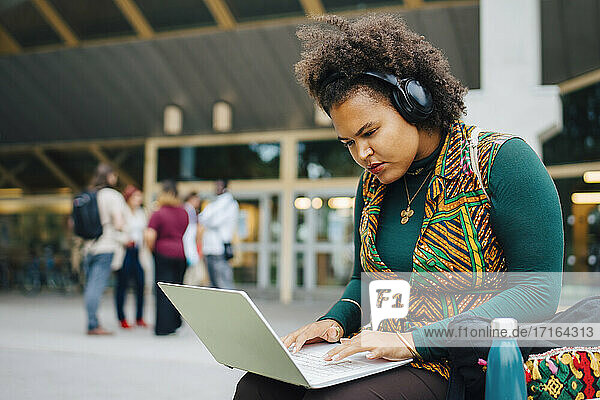 Weibliche Studentin konzentriert sich beim Online-Lernen über einen Laptop auf dem College-Campus