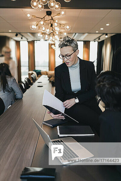 Reife Geschäftsfrau diskutiert über Dokument mit weiblichen Kollegen am Konferenztisch im Sitzungssaal