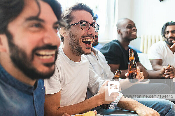 Man having beer and watching tv together  laughing