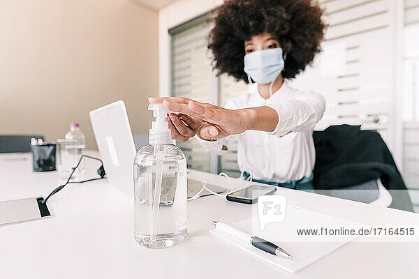 Businesswoman using hand sanitizer at her desk