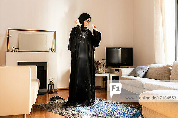 Junge muslimische Frau  stehend mit erhobenen Händen beim Gebet