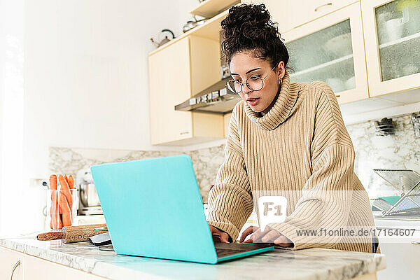 Junge Frau benutzt Laptop in der Küche