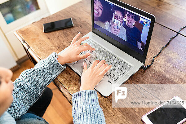 Junge Frau führt Videogespräch mit Freunden am Laptop