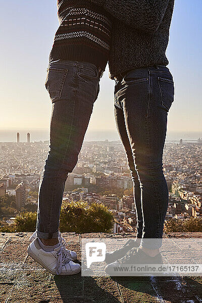 Beine von schwulen Männern  die auf einem Aussichtspunkt gegen den klaren Himmel in der Stadt stehen  Bunkers del Carmel  Barcelona  Spanien