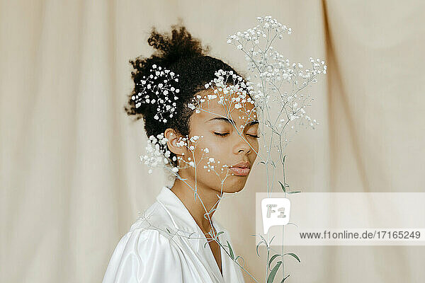 Weiße Blumen vor dem Gesicht einer jungen Frau