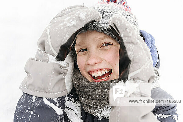 Close-up of cheerful boy playing with snow