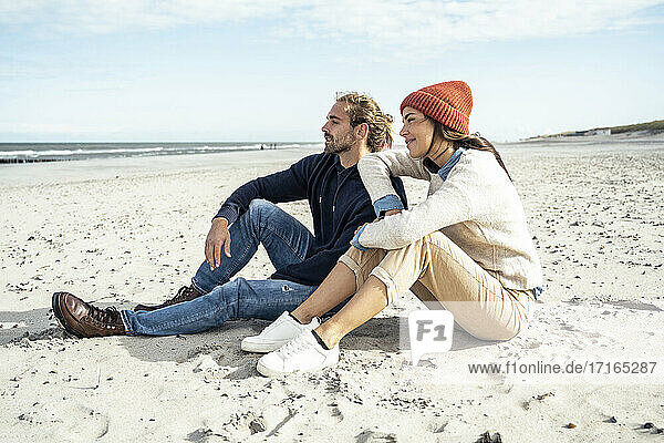 Young couple sitting together on beach sand