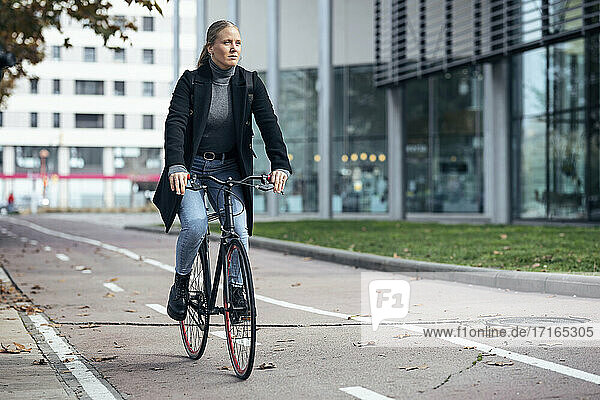 Woman doing cycling on road by modern building
