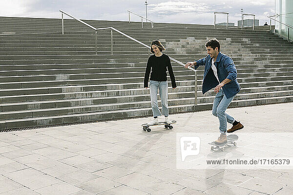Junges Paar auf dem Skateboard in der Nähe von Stufen