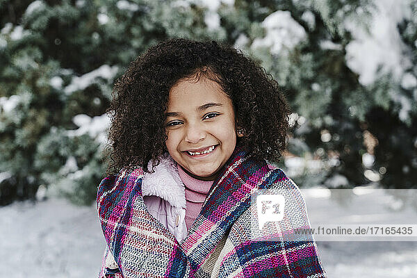 Lächelndes süßes Mädchen mit Schal im Park im Winter