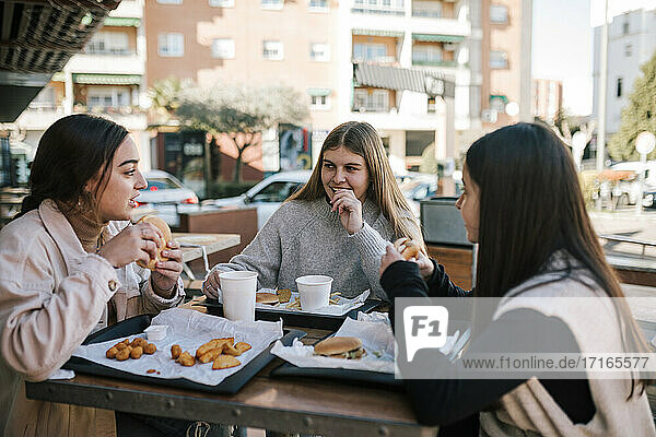 Weibliche Freunde beim schnellen Essen in einem Restaurant im Freien