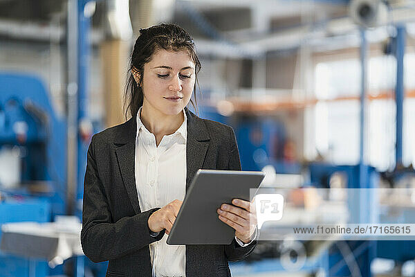 Businesswoman using digital tablet while standing at industry