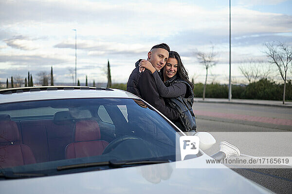 Paar umarmt sich  während es sich an ein Auto lehnt