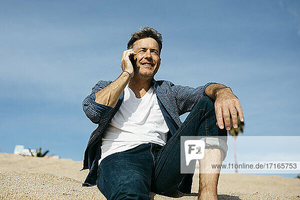 Mann spricht am Strand mit seinem Smartphone