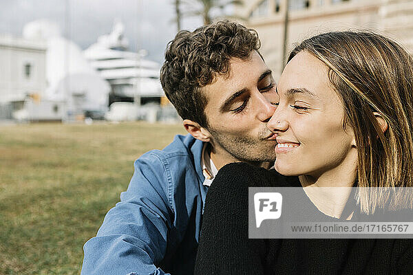 Young man kissing smiling woman outdoors