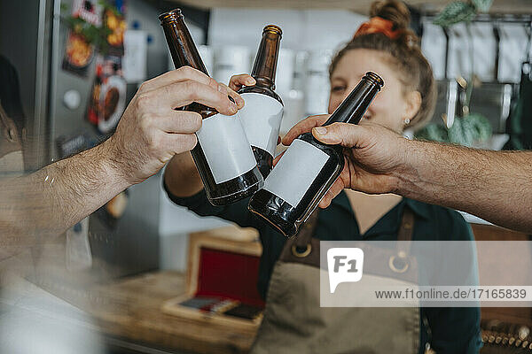 Chefs toasting beer bottles while standing in kitchen