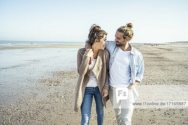 Junges lächelndes Paar  das sich beim Strandspaziergang am Wochenende ansieht