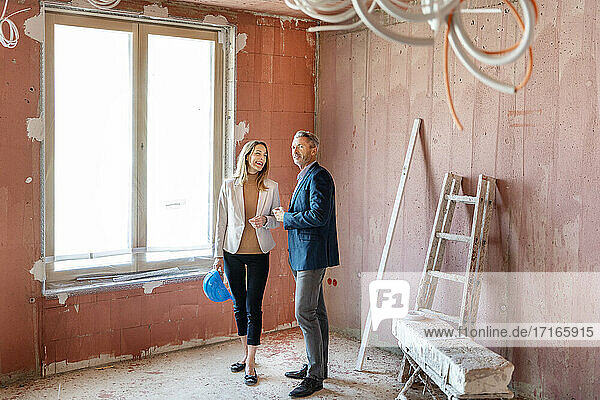 Männlicher Ingenieur und Geschäftsfrau arbeiten zusammen  während sie eine Baustelle untersuchen
