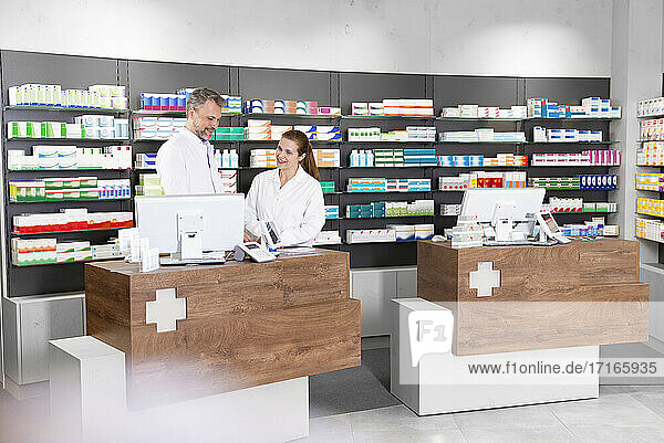 Male and female pharmacists working at pharmacy checkout